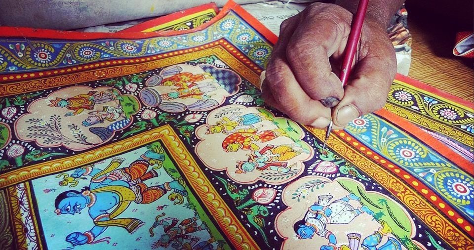 A chitrakar painting a Pattachitra scroll in the traditional Odia style
