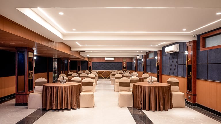 The banquet hall set with round skirted tables beneath a high ceiling