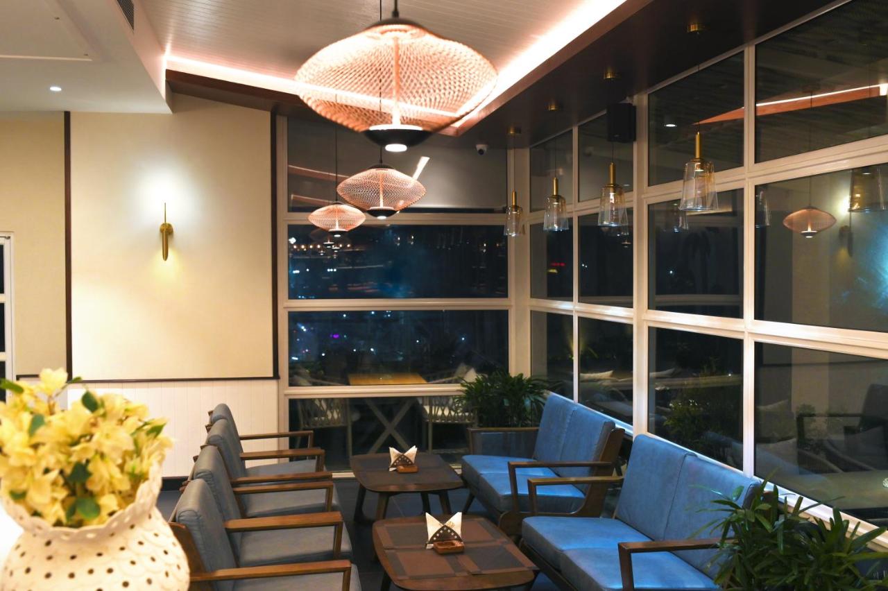Lobby with blue chairs, low tables and windows onto the grounds